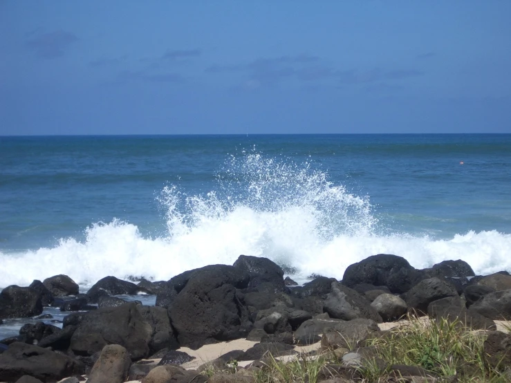 some rough rocks on the beach with crashing water