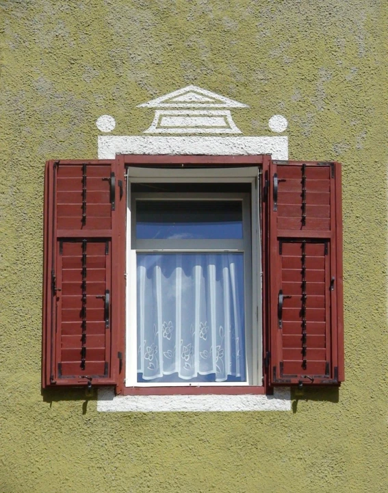 a window with red shutters and curtains below