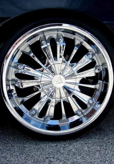 a silver wheel sitting on the ground next to a black car