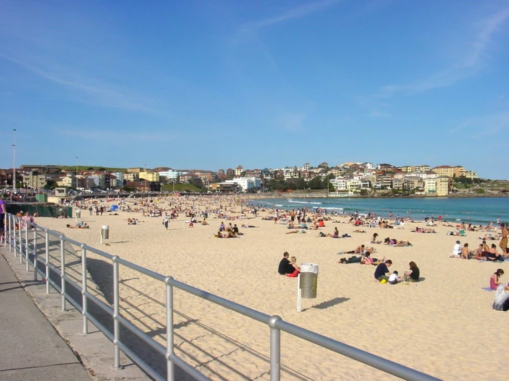 there are people standing on the beach near a railing