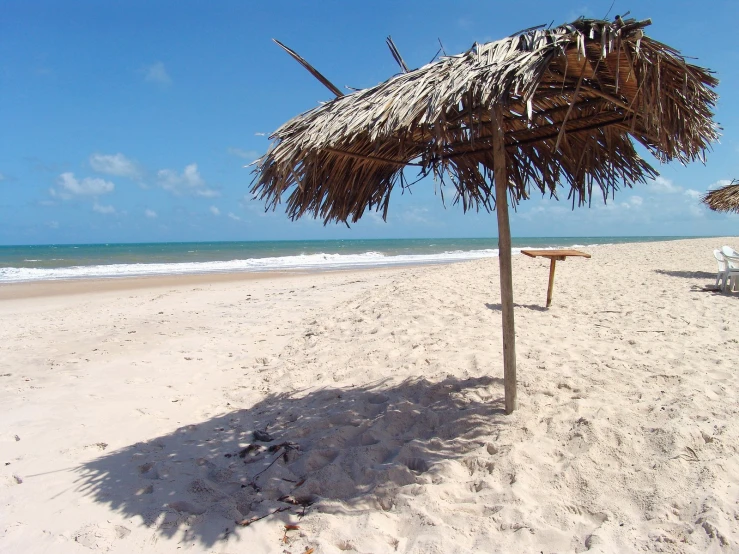 a large shade umbrella sitting in the sand on a beach