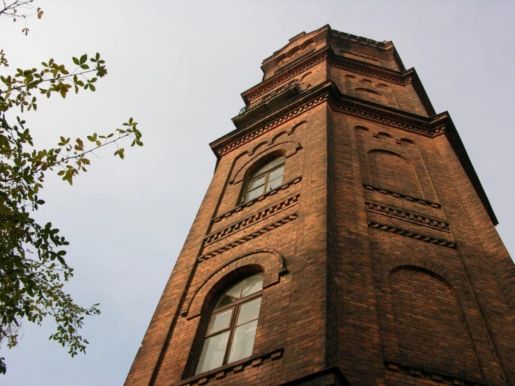 the top of a brown brick tower with some windows