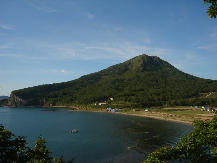 a view of a mountain side with small boats in the ocean