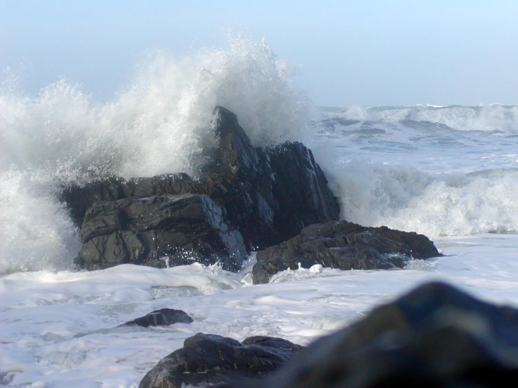 a wave hitting against rocks, in the ocean