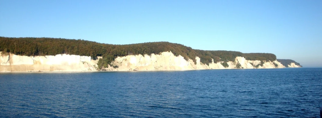 the coast of the ocean with cliffs and trees on the side