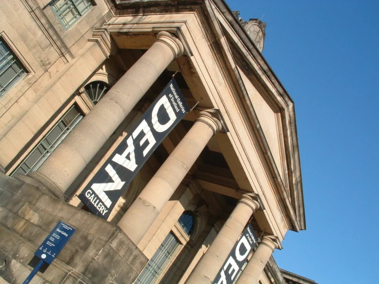 the front side of an old brown building with columns and signs on each of them