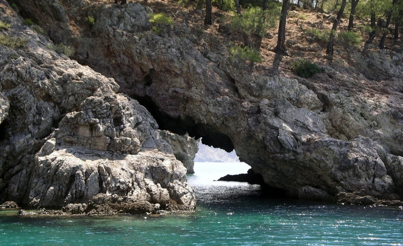 a cave entrance in the rock side with water coming out