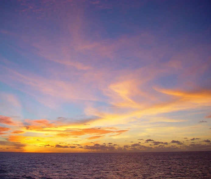 sunset over the ocean with an airplane above it