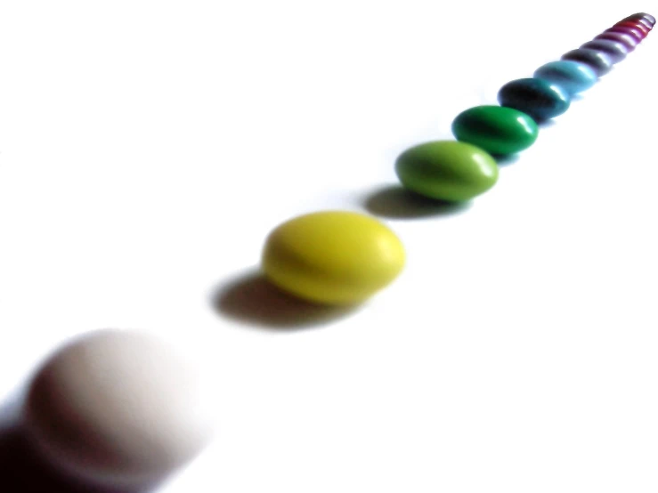 a multicolored line of six eggs sitting in front of a white background