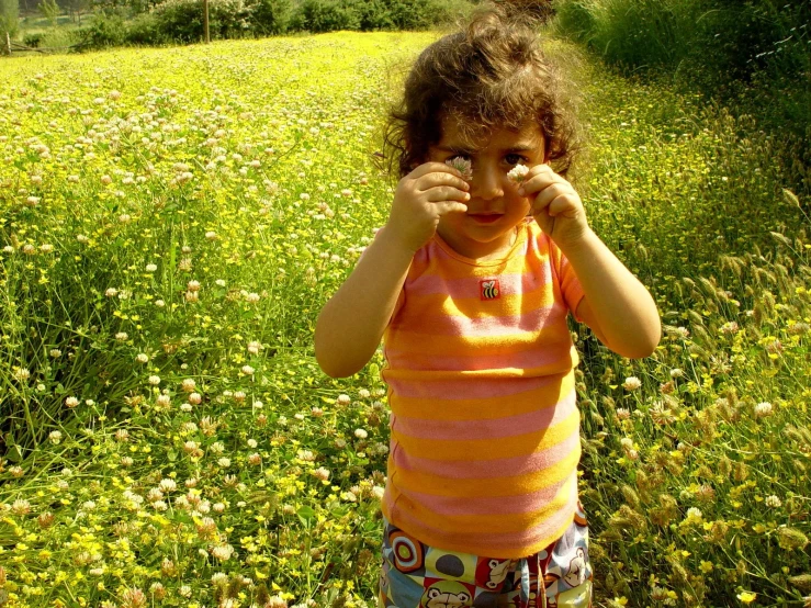 the little girl is standing in the field with her fingers up