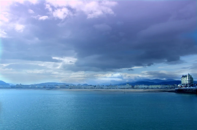 a body of water under cloudy skies next to the shore