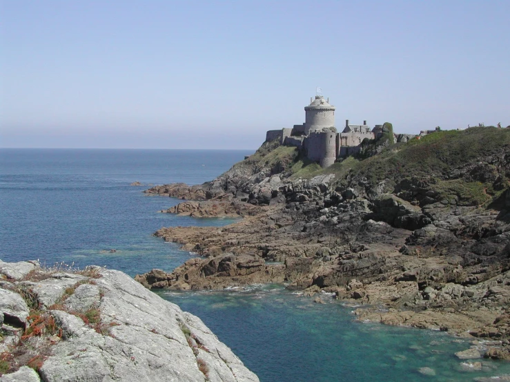 an ancient castle on a small rocky hill overlooking the ocean