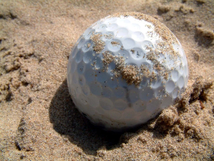 a golf ball is in the sand with sand flakes