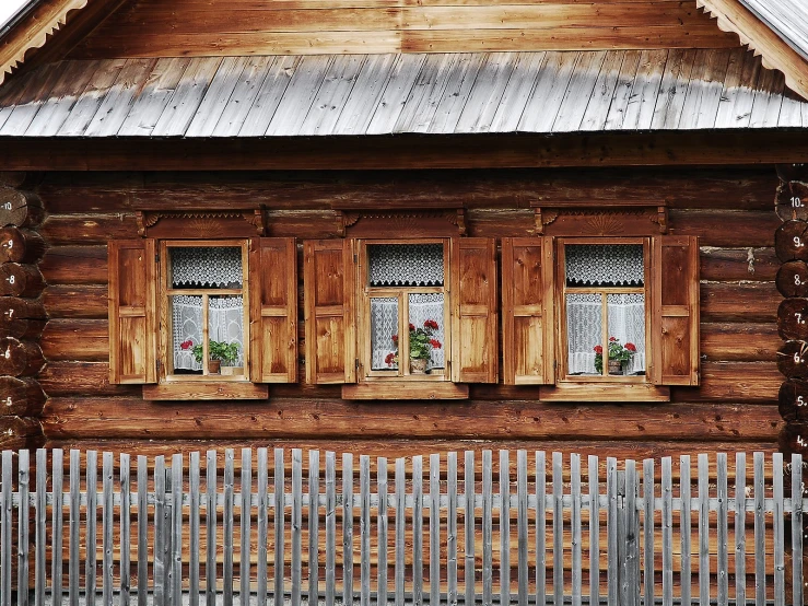 an old wooden cabin with three windows and a metal roof