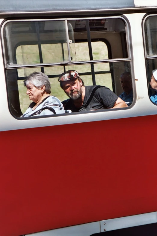 two older people are on a bus that looks like a passenger car