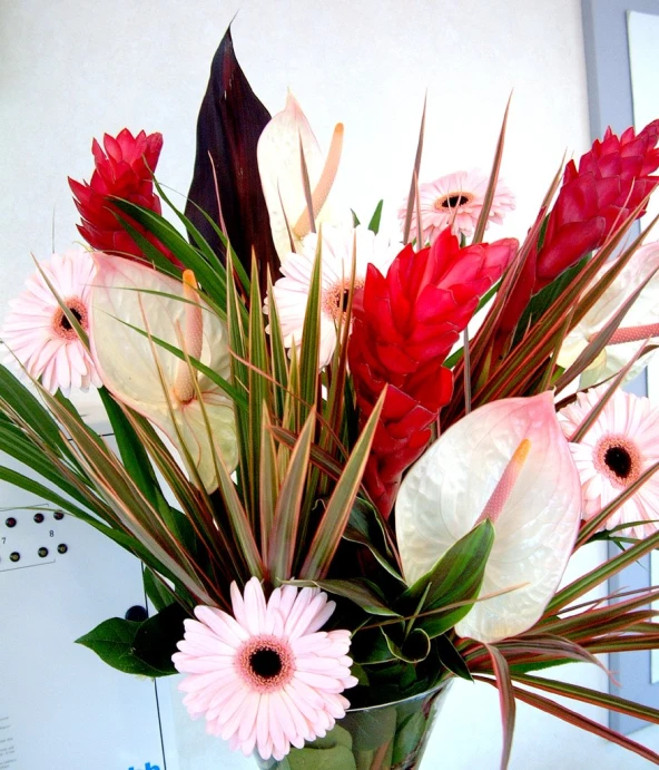 a vase filled with flowers and greenery sitting on a counter