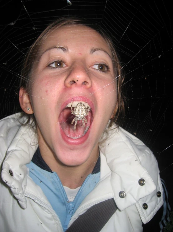 a young woman sticks her tongue out with a spider on it