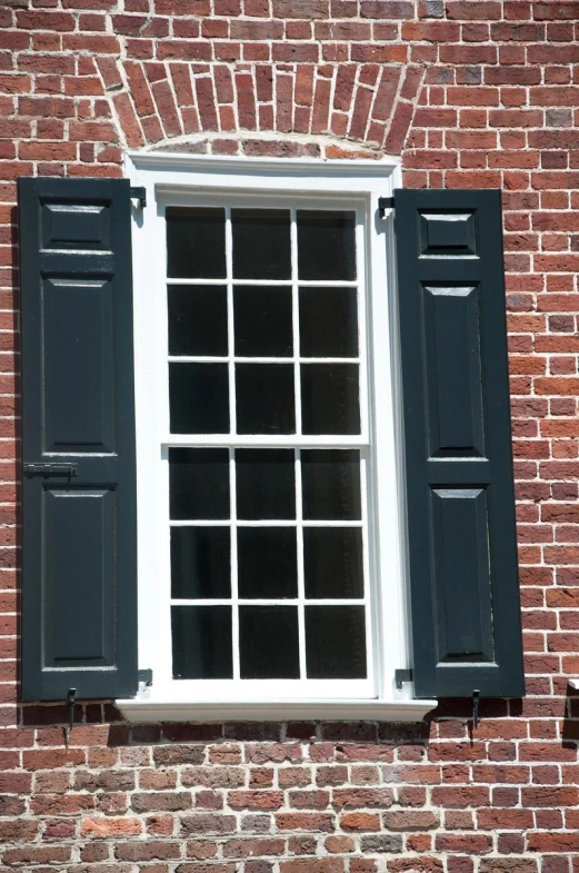 there is a small white window with shutters and two black pants underneath