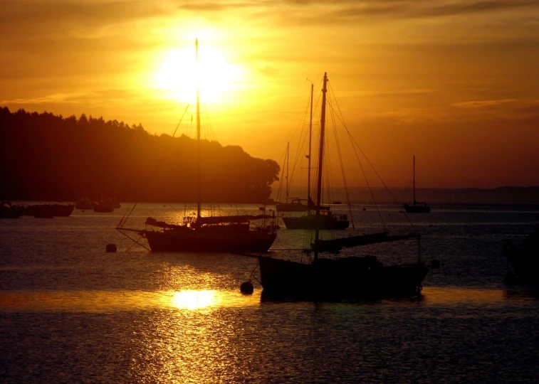 boats sit out on the water during the sun set