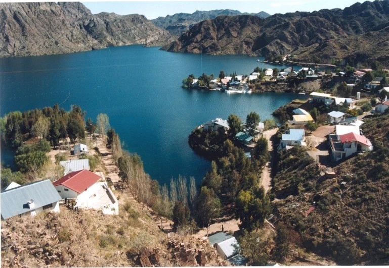 a large blue lake surrounded by mountains and houses