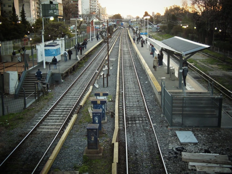 commuter train tracks near train station with people standing on the platform