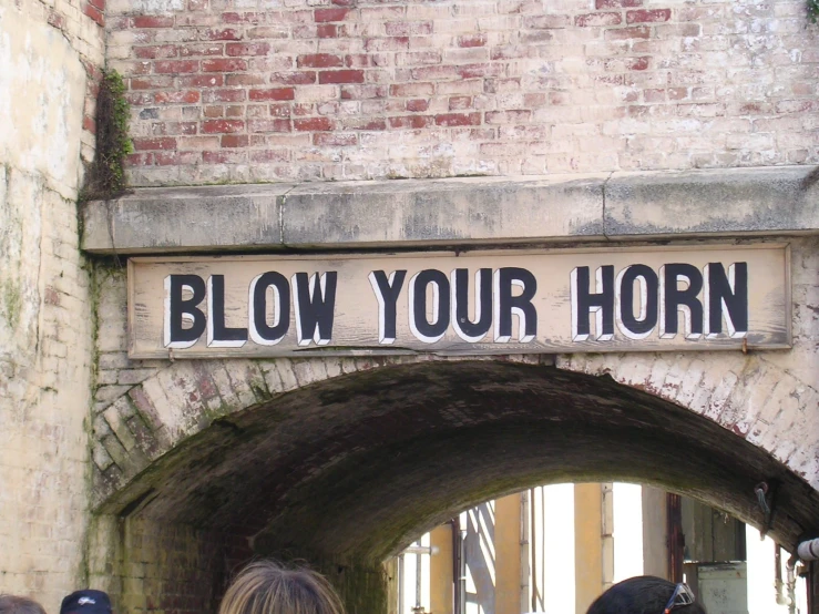 people are walking by the entrance to a tunnel with a sign on it saying blow your horn