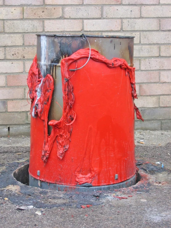 an orange trash can sitting by a brick wall