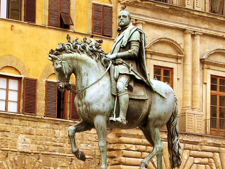 the statue is posed on the horse near the building