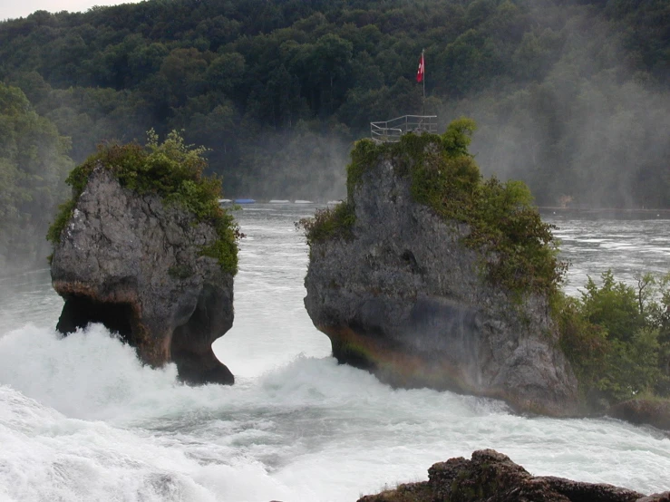 two large rocks sitting above a river that is rushing