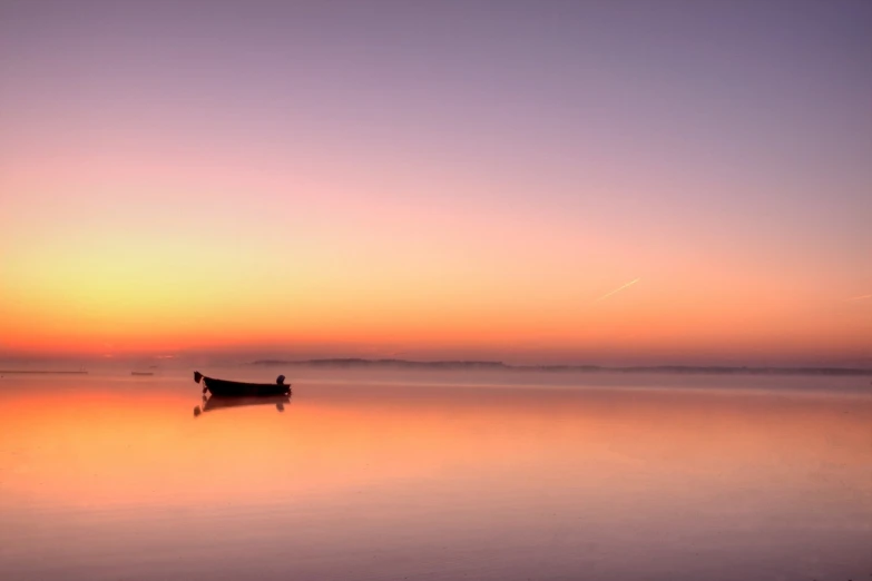 a small boat in a body of water at sunset