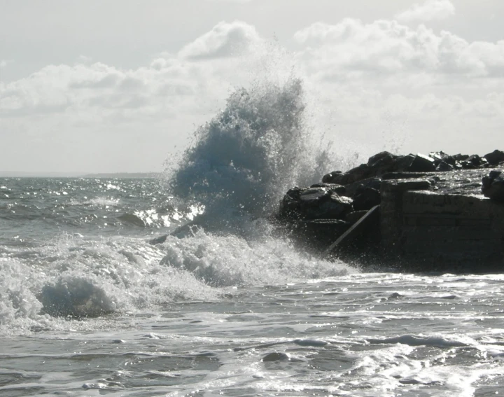 a man stands on a beach with his surfboard by the rocks