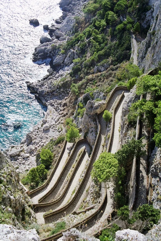 the cliff is beside the water with steps carved into it