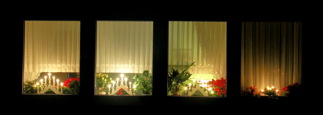 two candle lit candles sit on a window sill