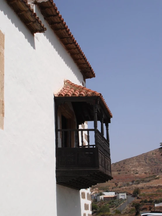 a white building with balcony next to mountains