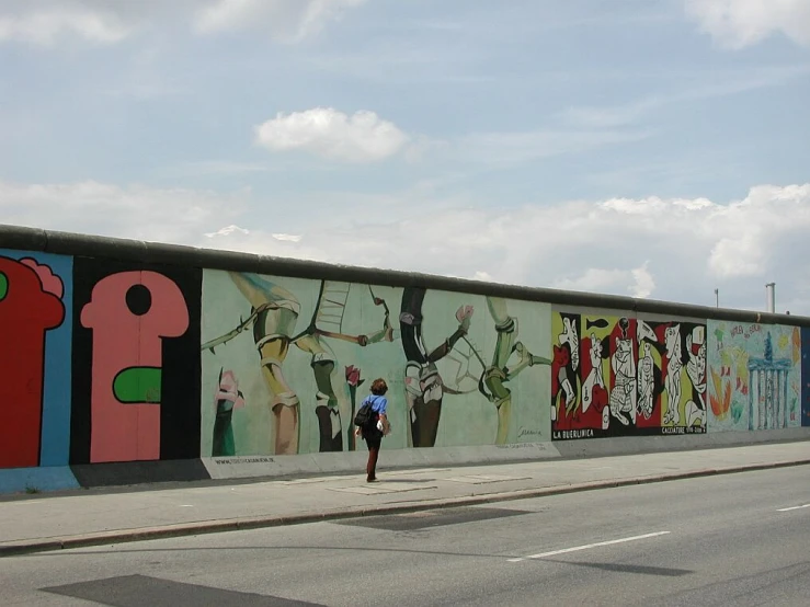 a man walking past a large mural of various colors