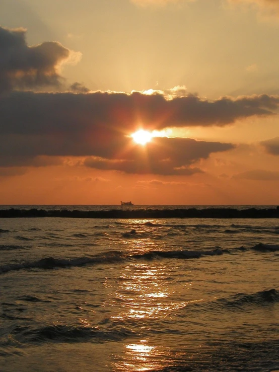 a sunset on a cloudy day near the ocean