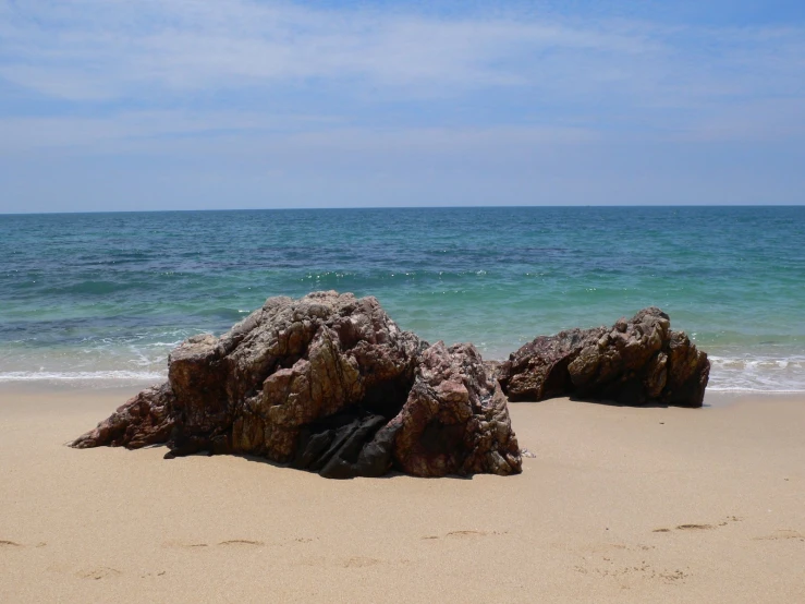 there are several rocks sticking out of the sand on the beach