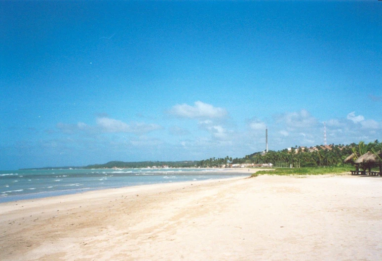 an empty sandy beach with houses in the distance