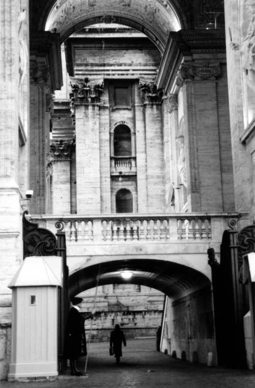 an image of man walking underneath a stone building