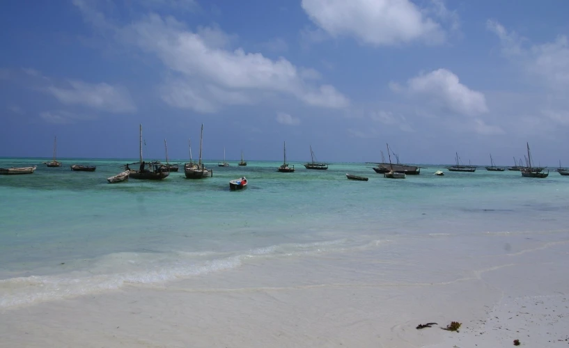 several boats out in the sea with an empty beach