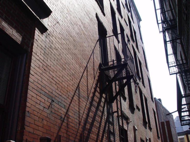 a tall brick building sitting next to a green fire escape