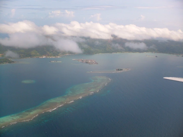 an airplane is flying low over the ocean and surrounding the island