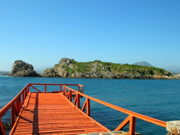 a red bridge is crossing the water to an island