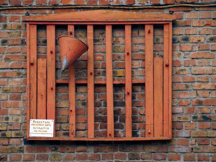 a brick wall with a wooden barred window and a sign