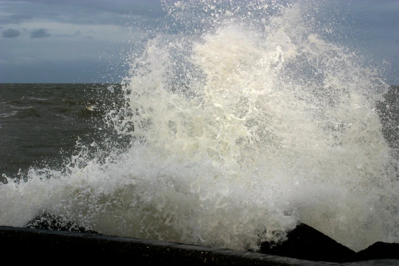 a large wave hitting on the beach with strong wind