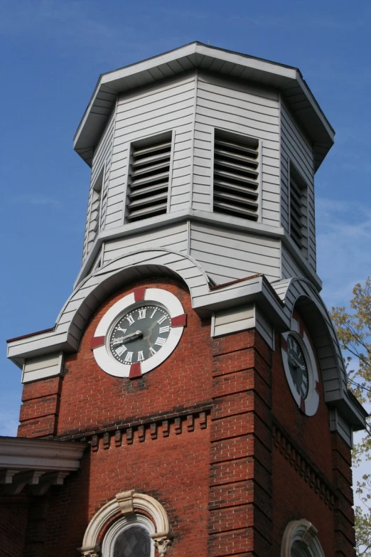 the steeple of a brick building has a clock on it