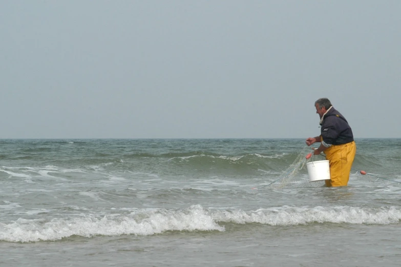 a man wading in the water with his bucket