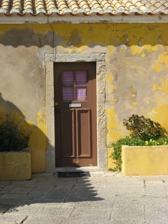 the small, yellow building has two planters on the outside