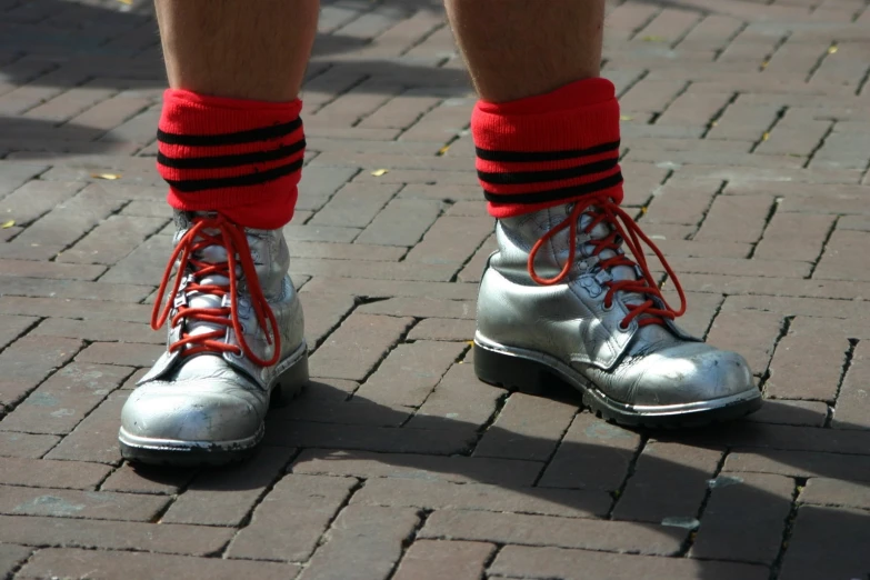 feet wearing boots on brick walkway and one with silver boots