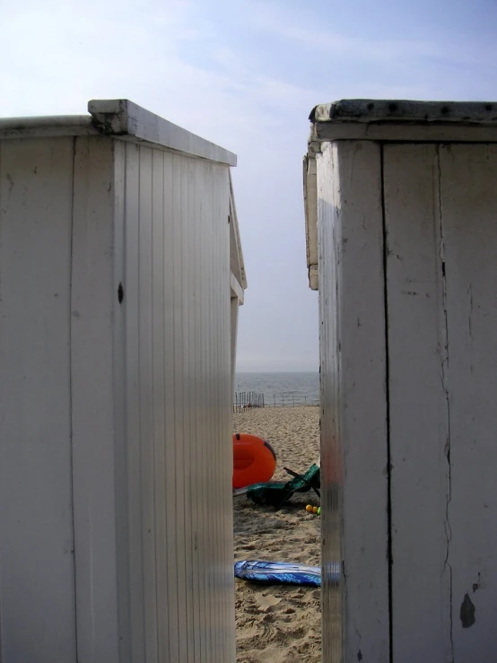 a doorway opens to the beach where a beach chair and a orange life jacket sit on it